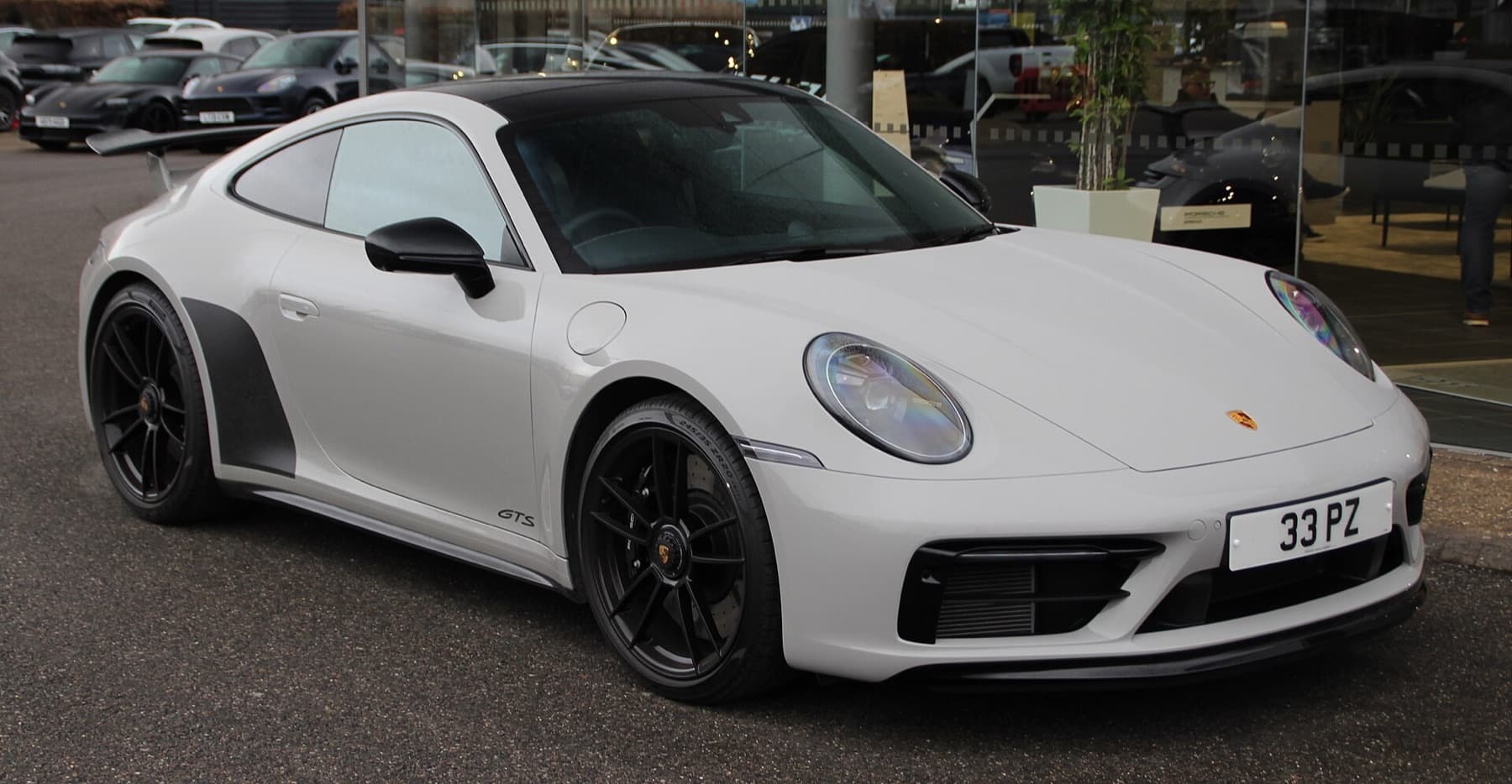 Porsche 911 in satin PPF, three-quarter front view in a dark studio.