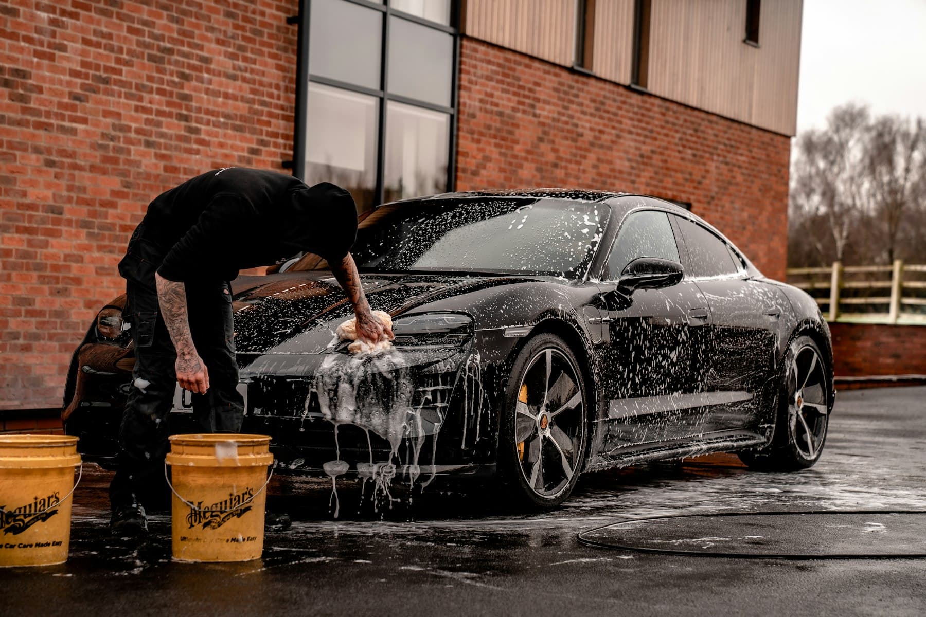 Wet, dark automotive paint under a narrow workshop lamp during a detail.